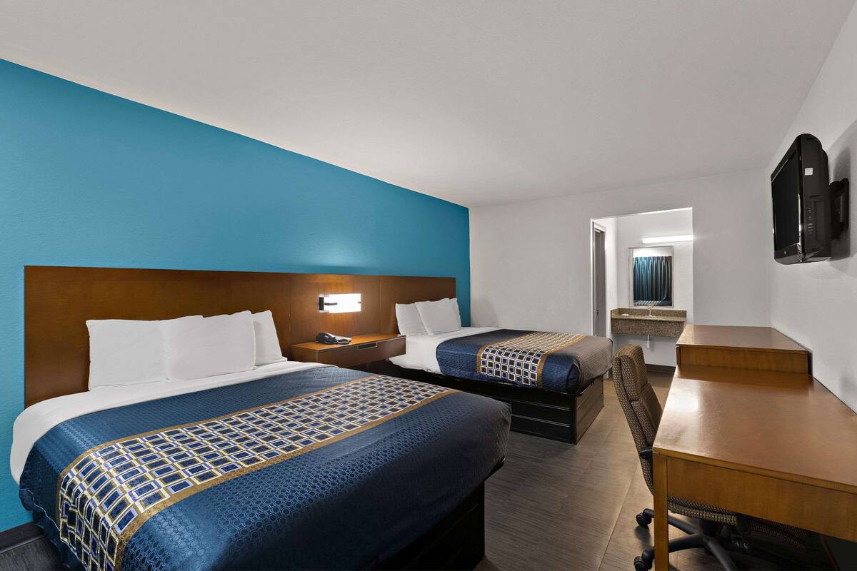Une chambre d’hôtel avec deux lits, un bureau et une télévision.