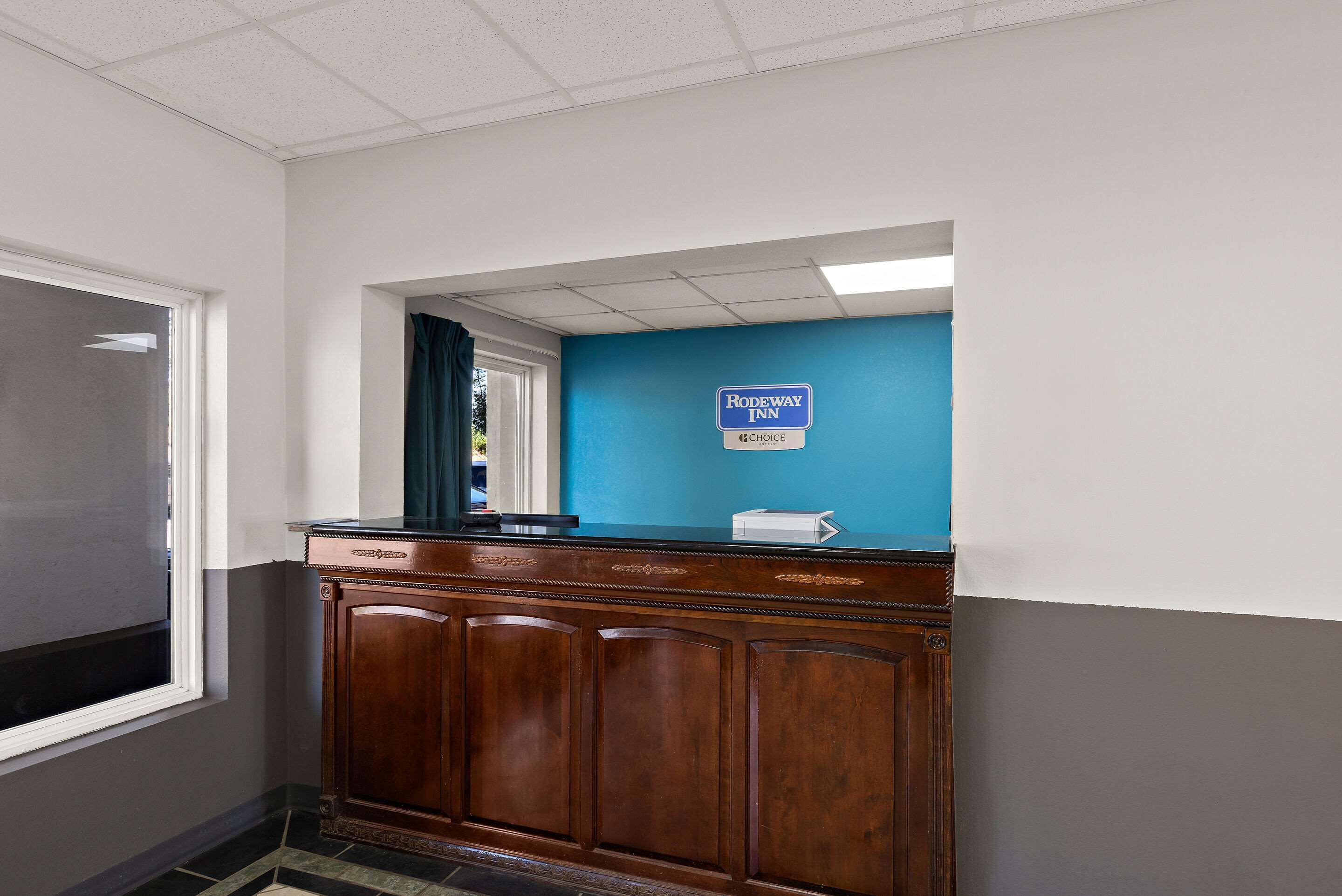 A reception desk with a blue wall and a sign reading "Rodeway Inn Choice".