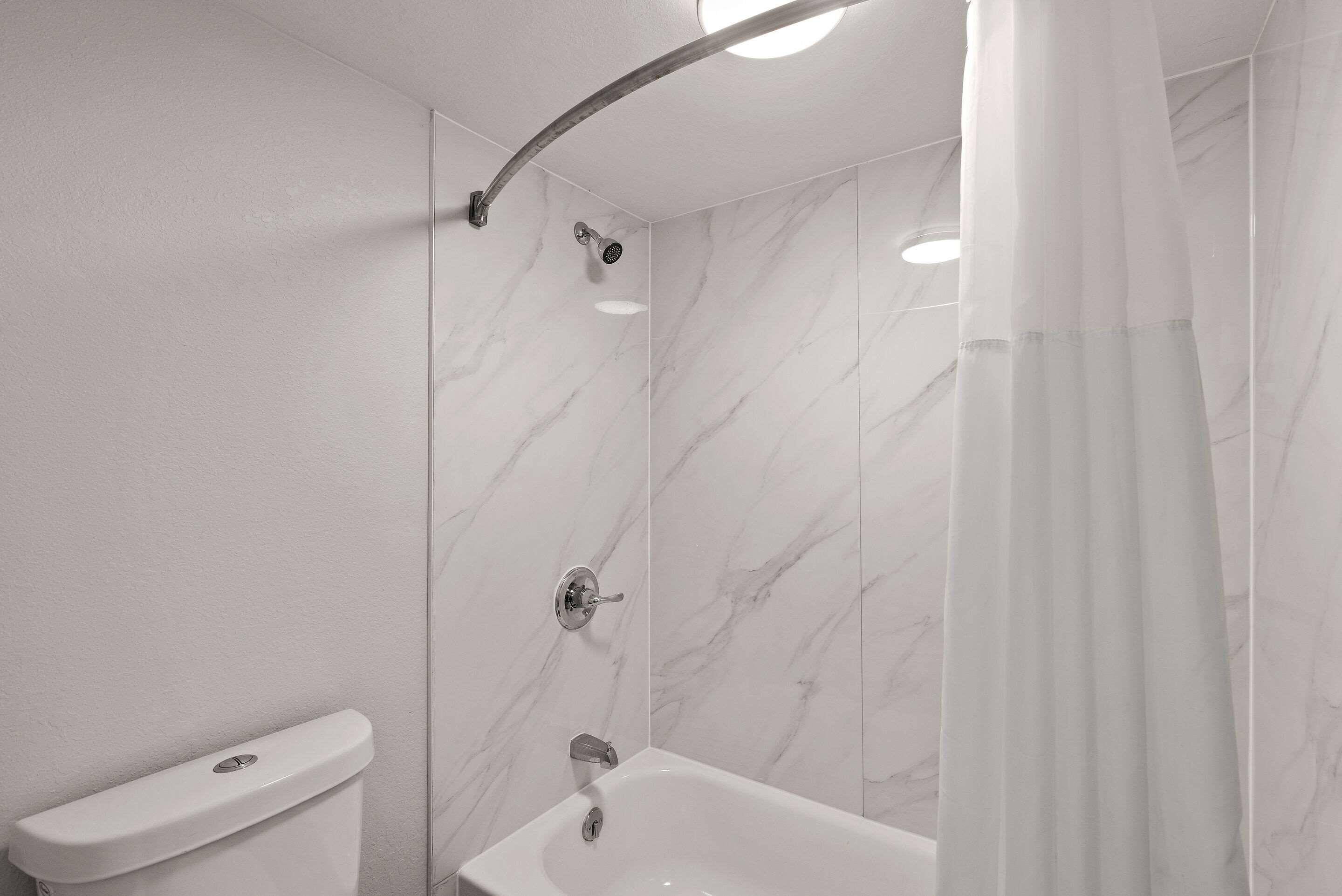 A modern bathroom with a shower, toilet, and bathtub.
