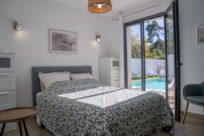 A bedroom with a bed, a desk, a chair, a pool view, and a door. - Spacious Luxury Villa with Pool – Walk to Beach – Ideal for Families or friends (Vaux-sur-Mer)