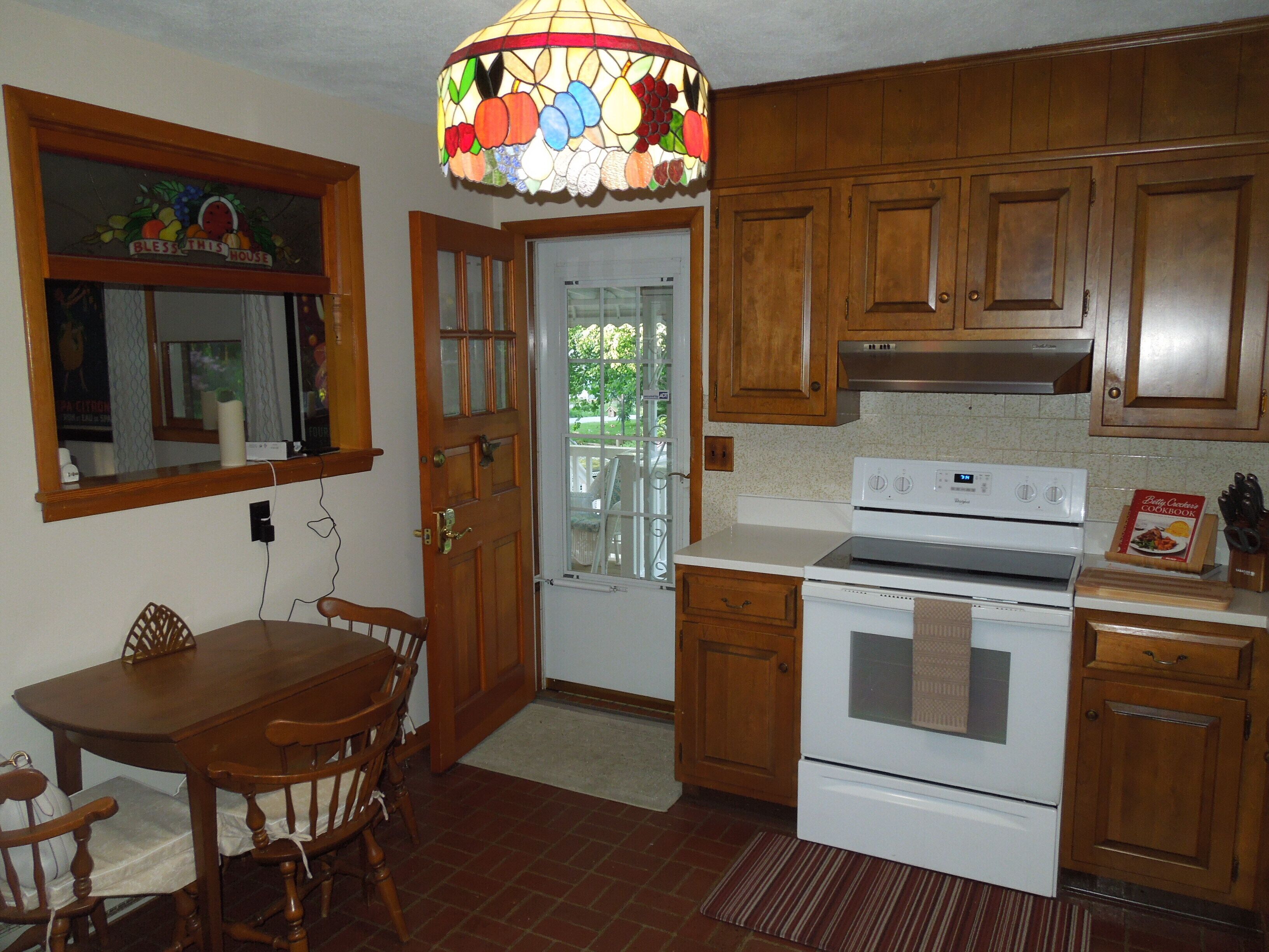 A kitchen with wooden cabinets, a white stove, and a stained glass light fixture.