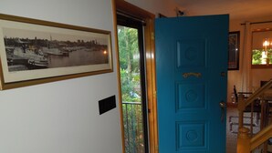 Uma porta azul com uma pequena janela, um quadro na parede e uma escada de madeira.