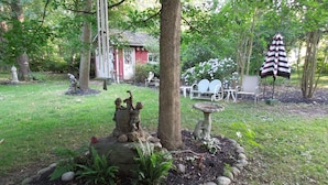 Um jardim com um elemento central de rochas, um bebedouro para pássaros e uma pequena estátua.