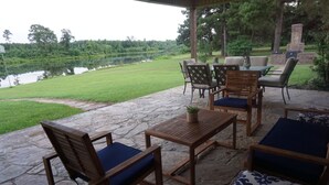 Une terrasse extérieure avec un sol en pierre, des meubles en bois et une vue sur un lac.
