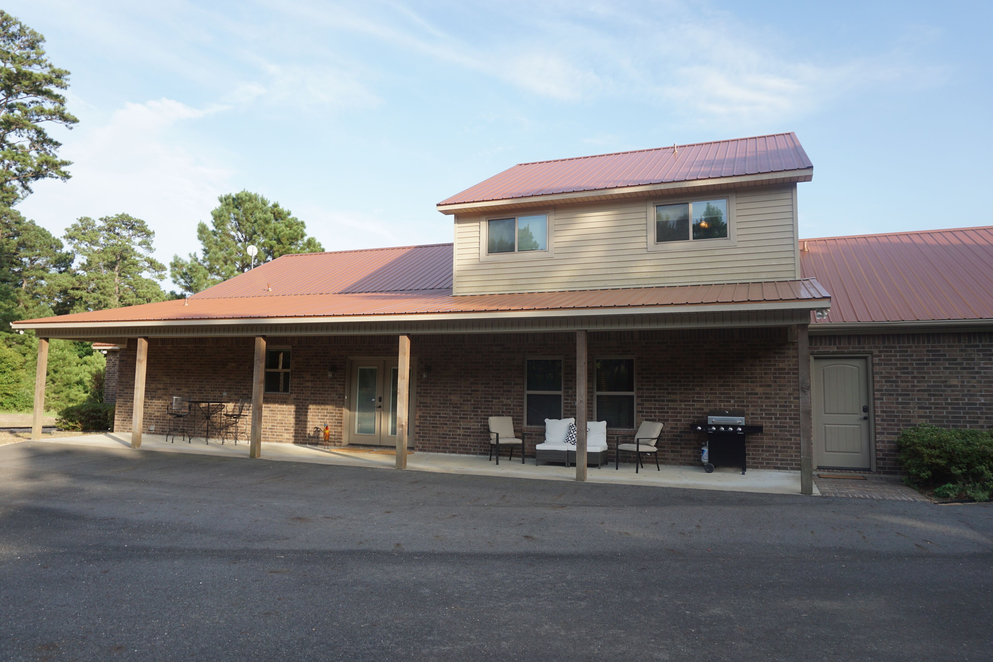 A two-story building with a covered patio area, outdoor seating, and a brick facade.