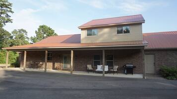 A two-story building with a covered patio area, outdoor seating, and a brick facade.
