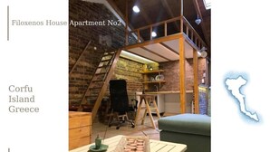 Een loft-appartement met onbehandelde bakstenen muren, een houten entresol en een eettafel met een schaal koekjes.