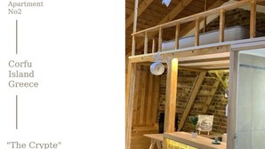 Een rustiek houten interieur met een vide, een kleine tafel met een plant en een hanglamp.