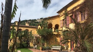 A courtyard with a paved patio, outdoor seating, and a building with arches and a tiled roof. - Very cosy villa with swimming pool 20 minutes from Nice (Drap)