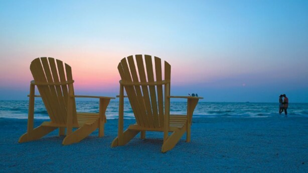 Two Adirondack chairs on a beach with a sunset in the background. - Beautiful family beach townhome getaway (Fernandina Beach)