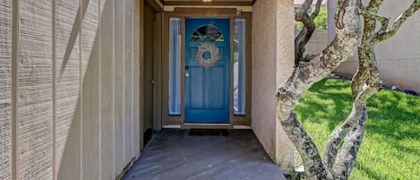 Entrada frontal com porta azul, número 15 e uma coroa de flores.