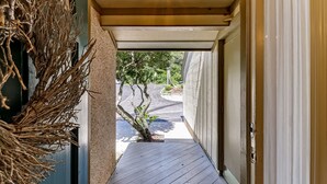 A narrow wooden pathway leading to a building entrance with a door and a small tree in the center. - Beautiful family beach townhome getaway (Fernandina Beach)