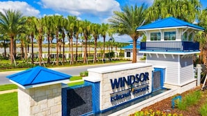 Placa do Windsor Island Resort, com vista clara das palmeiras ao redor e um edifício com telhado azul.