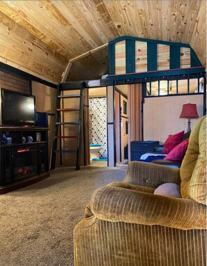 Cozy cabin living space with a comfortable sofa, small bed, and modern bathroom.