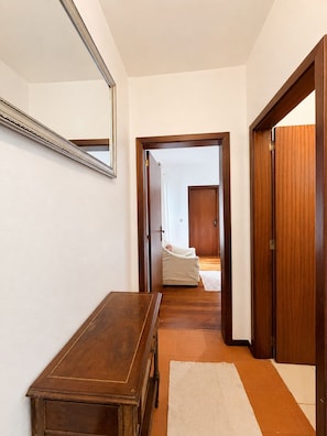 Ein Flur mit einer hölzernen Bank, einem Spiegel an der Wand und einer Tür zu einem Zimmer mit einem Bett.