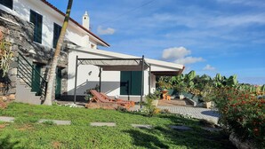 Uma casa moderna com fachada de pedra, um alpendre coberto e um jardim com piscina.