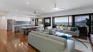A modern living space with a kitchen, dining area, and seating area with a view of the sea.