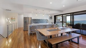 A modern kitchen with a built-in island, stainless steel appliances, and a view of the sea.
