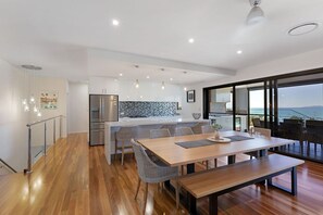 A modern kitchen with a built-in island, stainless steel appliances, and a view of the sea. - Lux On Nara (Airlie Beach)