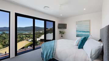 A bedroom with a large bed, a TV, and a painting.