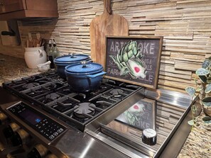 A kitchen with a gas stove, two blue pots, a wooden cutting board, a chalkboard with writing, and a potted plant. - Sun Drenched Tuscan home! 4 Bedrooms 4.5 Bathrooms, 2 Primary Suites, 2 Bedrooms (La Quinta)