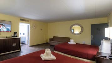 Quarto de hotel com duas camas, uma televisão, uma escrivaninha, um espelho e uma porta.