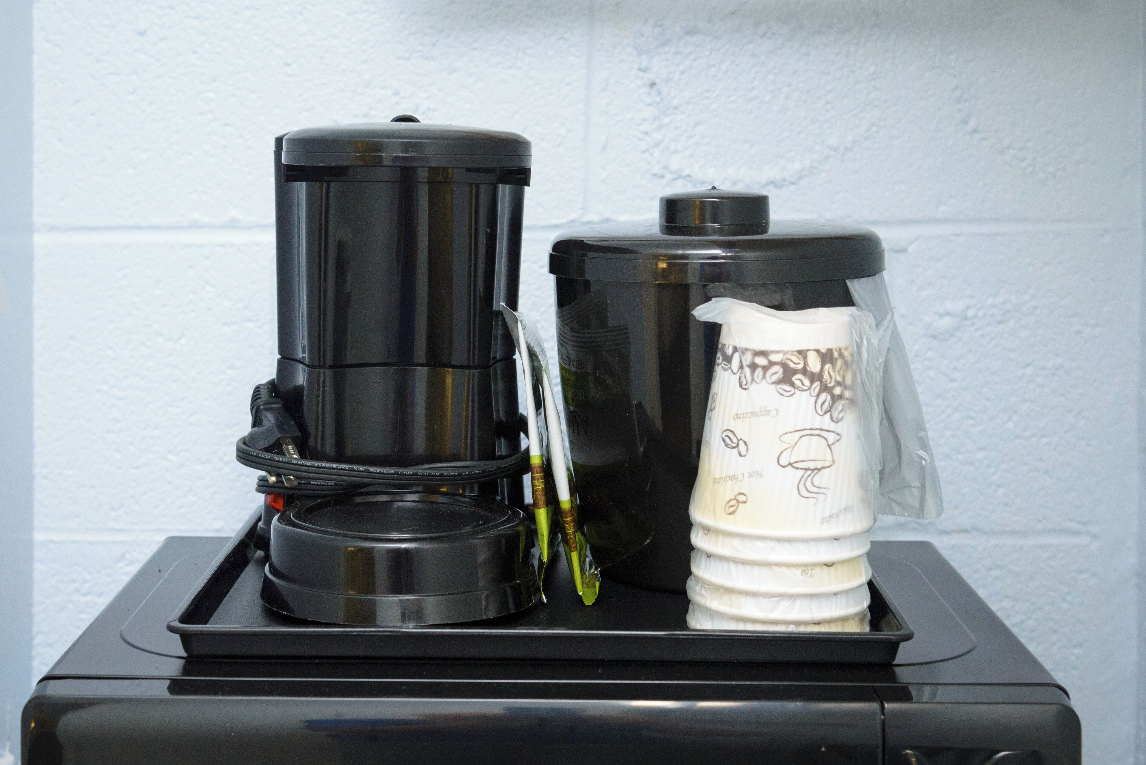 Une machine à café et un mousseur à lait sont posés sur un plan de travail noir.