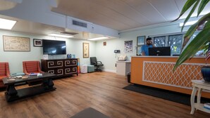 Un espace d’accueil doté d’un plancher en bois, d’un comptoir de réception, d’un téléviseur et d’une chaise.