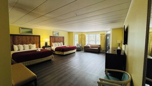 Une chambre d’hôtel avec deux lits, un canapé, une chaise, un bureau et une télévision.