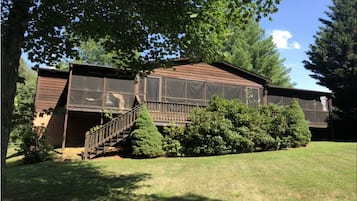 Stroll up to this charming two-story home, featuring a spacious porch and a staircase leading to a bright upper level with large windows.