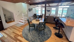 A spacious living area with a wooden ceiling, a round dining table with chairs, a sofa, and a bar area. - Spacious 3 Bedroom, 2 bath, new home, ocean views, close to Maine seafood! (Orr's Island)