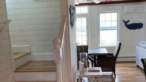 A staircase with white railings leading to a dining area with a table and chairs. - Spacious 3 Bedroom, 2 bath, new home, ocean views, close to Maine seafood! (Orr's Island)