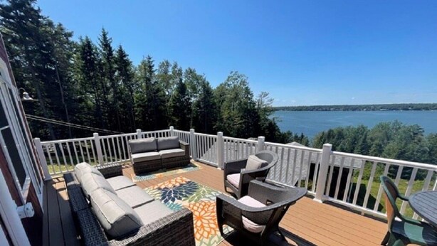A deck with outdoor furniture, a view of a lake, and a white railing. - Spacious 3 Bedroom, 2 bath, new home, ocean views, close to Maine seafood! (Orr's Island)