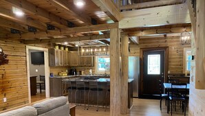 A spacious kitchen with wooden beams, a bar area, and a dining table with chairs.