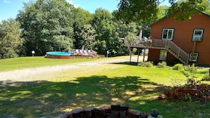 A backyard with a fire pit, a wooden deck, and a swimming pool.