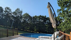 A pool area with lounge chairs and a wooden deck.