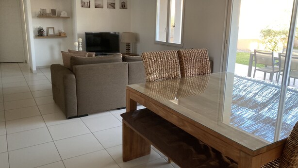 A modern living room with a sofa, a glass-top coffee table, and a television. - Villa with garden in charming village near Avignon (Entraigues-sur-la-Sorgue)