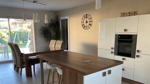 A modern kitchen with white cabinets, a wooden island, and a built-in oven. - Villa with garden in charming village near Avignon (Entraigues-sur-la-Sorgue)