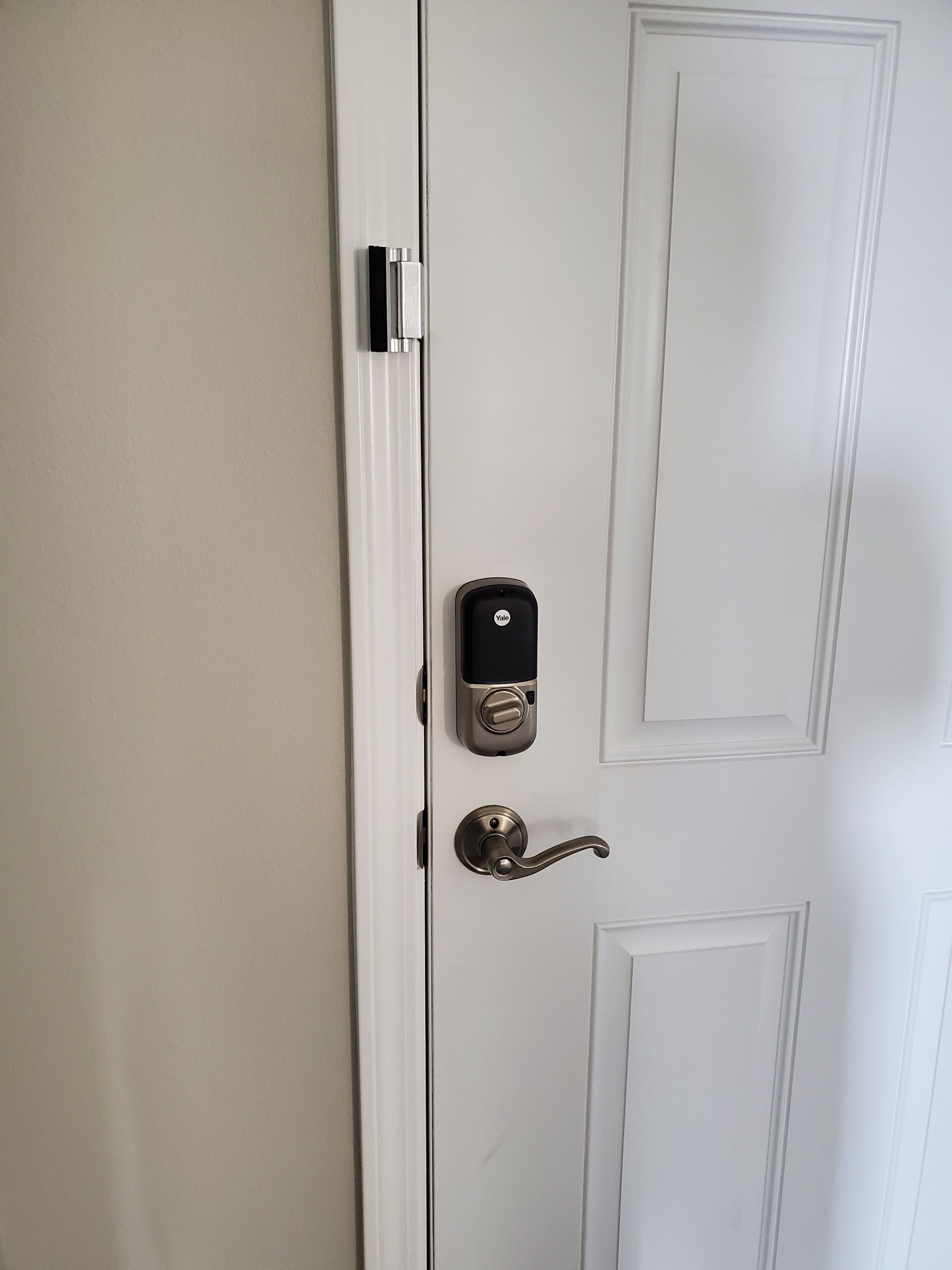 A white door with a Yale smart lock and a lever handle.