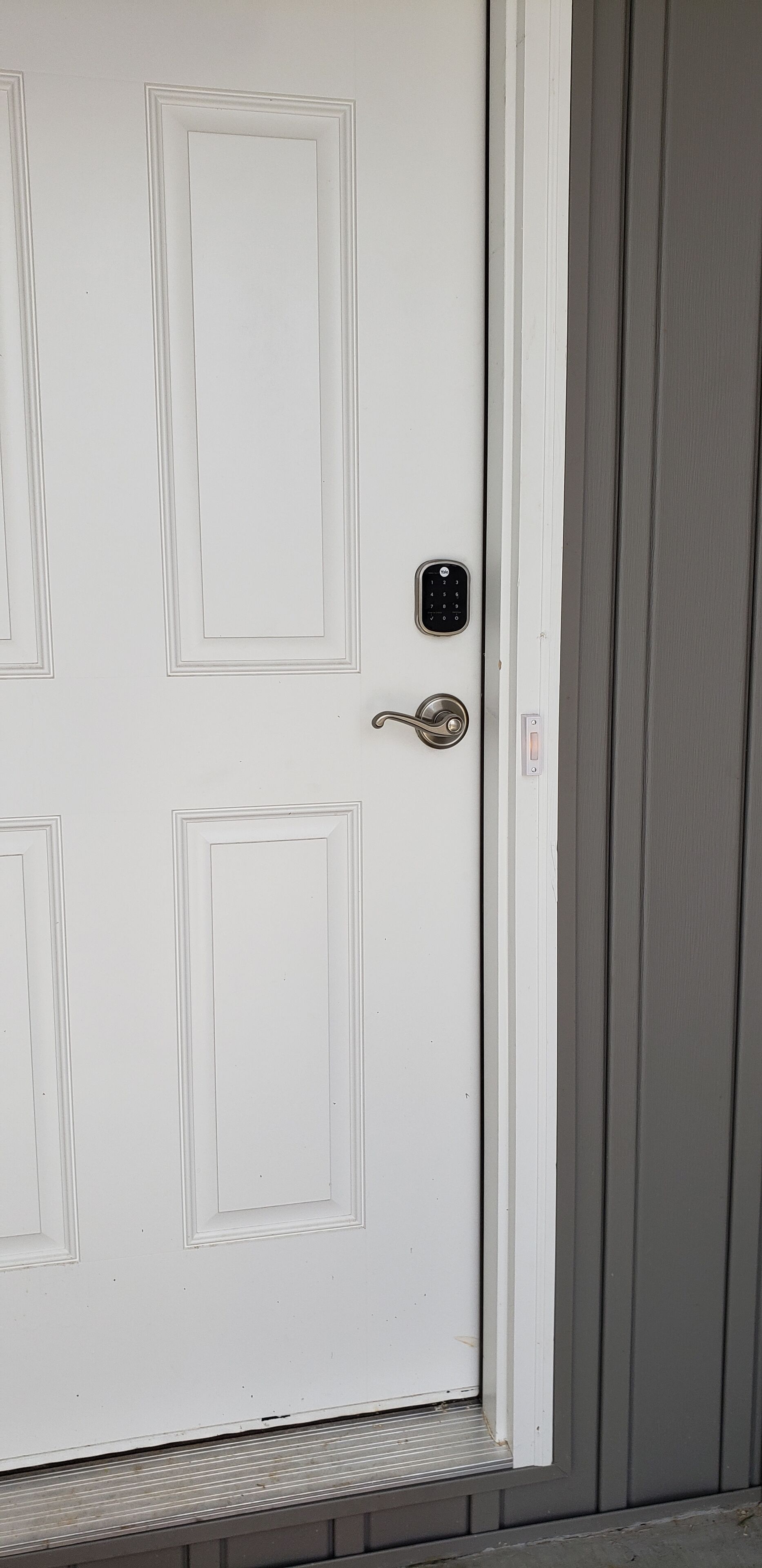 A white door with a keypad lock and a keyhole.