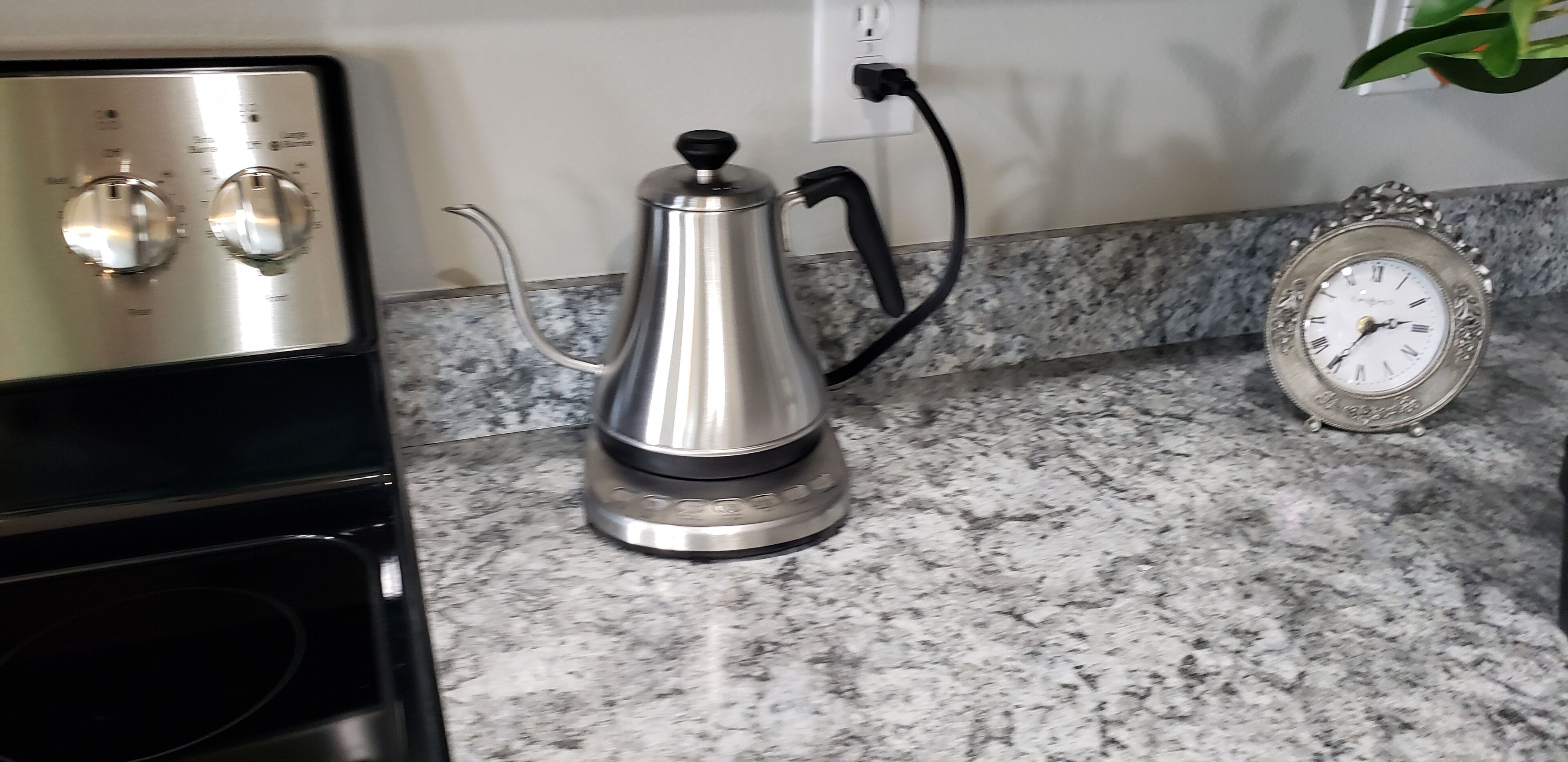 Una cocina con cafetera, un reloj y estufa.