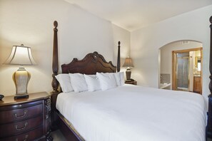 Ein ordentlich gemachtes Bett mit weißen Leinentüchern, einem Holz-Kopfteil und zwei Nachttischlampen.