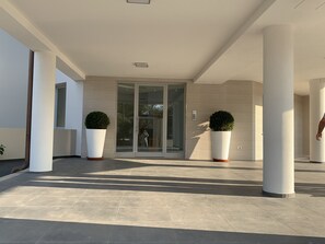 A modern building entrance with a glass door, large potted plants, and a tiled floor. - Apartment with a panoramic view of the sea in the Gulf of Olbia (Olbia)