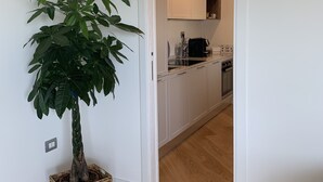 Een moderne keuken met witte kasten, een ingebouwde oven en een koffieapparaat.