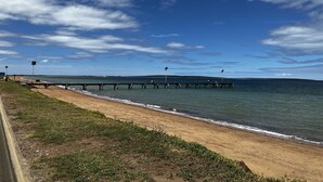 A coastal scene with a sandy beach, a pier extending into the water, and a clear sky with scattered clouds. - Beautiful private beachfront home overlooking the stunning Boston Bay and PL (North Shields)
