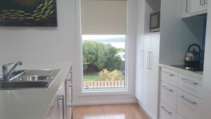 A modern kitchen with a large window, wooden flooring, and white cabinetry. - Beautiful private beachfront home overlooking the stunning Boston Bay and PL (North Shields)