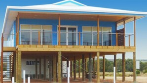 A two-story building with a balcony on the ground floor and a covered upper floor. - Beautiful private beachfront home overlooking the stunning Boston Bay and PL (North Shields)
