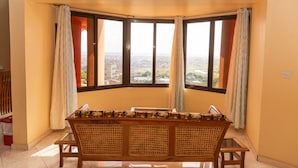 A room with a bay window, a wooden bench, and a clock on the wall.