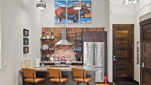 Una cocina con protector mural de ladrillo, electrodomésticos de acero inoxidable y una zona de bar con taburetes.