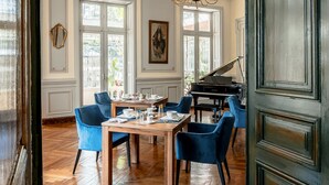Una habitación amplia con piso de parqué tipo espiga, un piano de cola y un candelabro.
